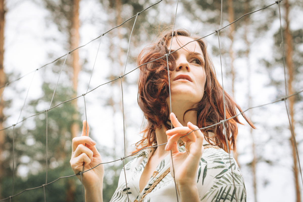 Woman standing at fence in forest